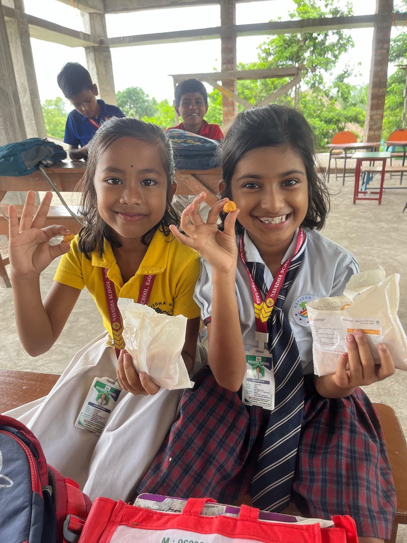 Two schoolgirls beam as they hold up their packets of the nutrition mix.