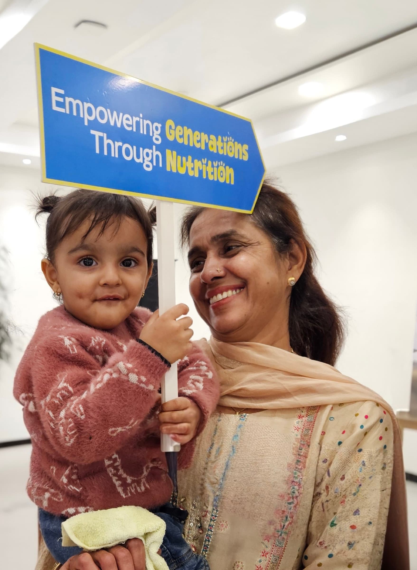 A mother holds her small child at a community nutrition event.