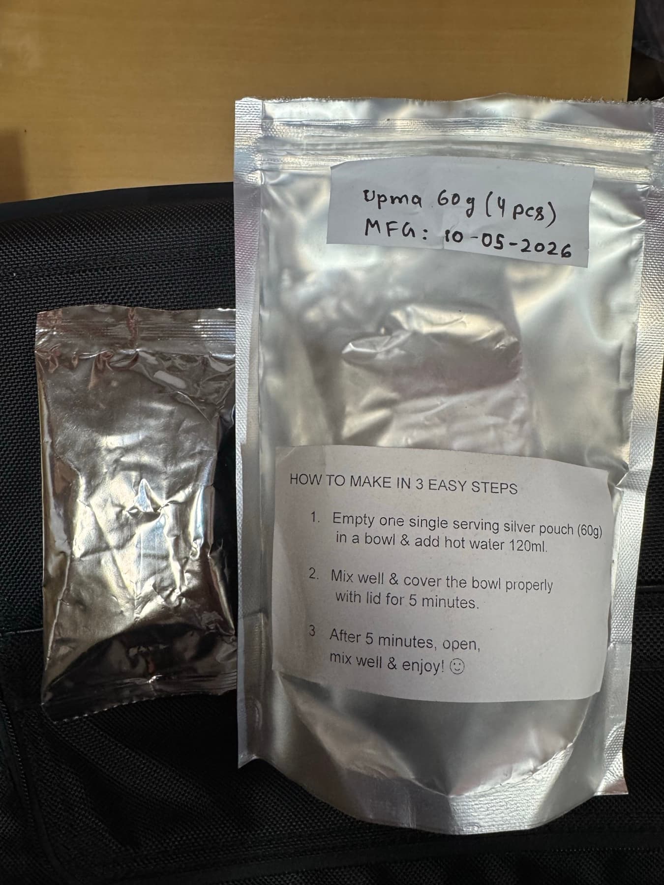 Two real foil packs of TBR breakfast on a table, a single-serving sachet and a larger resealable pack with its own printed three-step prep instructions.